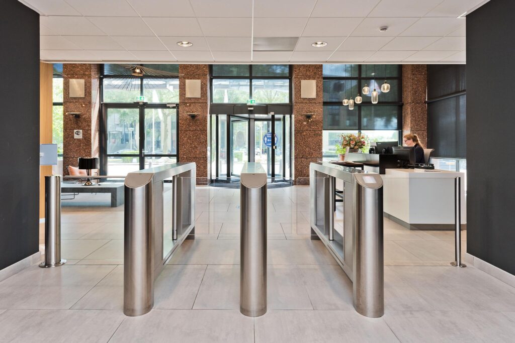 Moderne entreehal met een receptiebalie, toegangspoortjes en een draaideur aan de Prof. W.H. Keesomlaan.